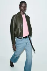 Chaqueta estilo bomber de efecto piel en color verde oliva, con cuello solapa, cierre frontal con cremallera, mangas largas y bajo elástico.