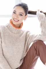 Sweater de punto color beige con cuello alto y ribete naranja en cuello y puños.