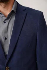 Blazer de corte slim fit confeccionado en pana de textura suave, con cierre frontal de dos botones, solapas clásicas y bolsillos laterales con solapa.