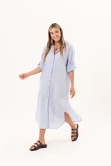 Vestido camisero largo color celeste, de silueta relajada con abotonadura frontal completa, cuello camisero y mangas regulables. Presenta tajos laterales y detalle de bordado sutil en la manga.