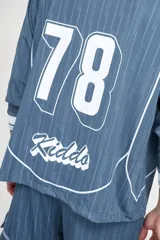 Camiseta de fútbol celeste con rayas verticales, cuello polo y mangas 3/4 con puños blancos. Incluye el número 78 en el frente y logos estampados.