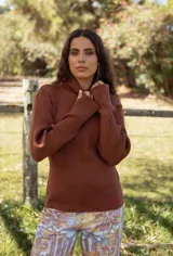 Polera de tejido de punto acanalado color chocolate, con cuello alto y mangas largas. Presenta un pequeño bordado en el ruedo inferior.