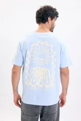 Remera celeste de manga corta y cuello redondo, con gran estampado en la espalda de un sol, ondas y diseño a cuadros con el texto "SUNSET STATION".