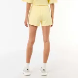 Pantalón corto de felpa color amarillo pastel, de tiro medio con cintura elástica ajustable mediante cordón y diseño holgado.