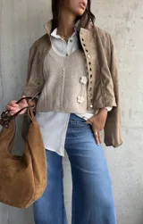 Chaleco de punto color beige con escote en V, diseño de trenzas verticales y tres flores tejidas en relieve.