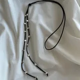 Corbatín negro de tiento largo con dijes de estrellas plateadas.