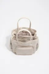 Bolso tipo tote y bandolera de color beige, con bolsillos externos con cierre y asas de mano y hombro.