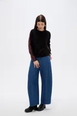 Sweater de viscosa con diseño color block, combinando frente negro con mangas y laterales en tono marrón. Presenta cuello redondo a la base y mangas largas.