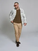 Camisa de manga larga confeccionada en algodón, con diseño de cuadros en tonos blanco y verde oliva. Presenta cuello clásico con botones y cierre frontal abotonado.