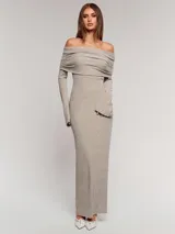 Vestido largo de punto acanalado en color beige, con diseño de hombros descubiertos y cuello solapado. Presenta mangas largas y un corte ajustado al cuerpo.