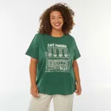 Remera de algodón color verde oscuro, corte holgado y manga corta, con estampado frontal en blanco que simula la fachada de un café parisino con el texto "CAFÉ PARISIEN".