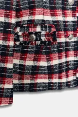 Blazer Zara Woman Collection de corte entallado con bajo peplum, confeccionada en tejido de mezcla de algodón con estampado de cuadros en tonos rojo, azul marino y blanco. Presenta cuello solapa, manga larga, bolsillos delanteros y cierre frontal con botones metálicos en relieve.