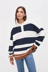 Buzo de punto con diseño de rayas horizontales en azul marino y blanco, con cuello polo, cartera de botones y detalle de franja en color marrón en el ruedo y puños.