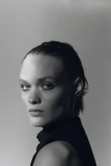 Vestido midi negro sin mangas, con cuello subido y detalle de drapeado en el delantero. Cierre en la espalda con cremallera oculta.