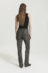 Pantalón de gabardina elastizada con estampado abstracto en tonos dorados y negros. Tiro medio, acceso con cierre metálico y botón jeanero. Bolsillos delanteros jeaneros y con cierre metálico en diagonal oculto. Bolsillos plaque en espalda. Pierna con recortes pisados con doble pespunte. Pierna flaire con leve campana en botamanga.