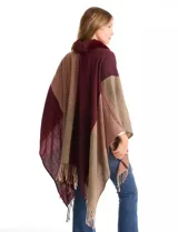 Ruana tejida con diseño de bloques de color en tonos tierra y bordó, con cuello de piel sintética en color bordó y terminación de ruedo con flecos.