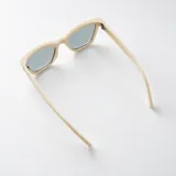 Lentes de sol Duna con armazón de policarbonato color beige y diseño rectangular con esquinas levemente angulares. Lentes oscuros con filtro UV400 y patillas gruesas.