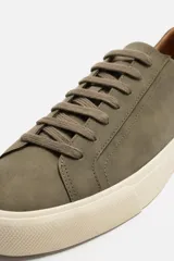 Zapatillas de cordones color verde oliva, con parte superior lisa, horma redonda, forro interior a contraste y suela con ligera textura.