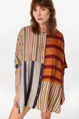 Vestido camisero corto con diseño de paneles combinados en distintos patrones de rayas verticales y horizontales, en tonos rojo, azul, beige y blanco. Posee cuello mao, cierre frontal con botones y mangas cortas caídas.