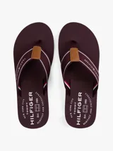 Ojotas de hombre con base de goma EVA color bordó y detalles de líneas rojas y blancas en el borde. Las tiras son de tejido trenzado bordó con franjas blancas y rojas, y tienen un aplique de cuero sintético marrón en el centro.