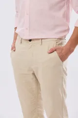 Pantalón de lino color beige, de corte recto y cintura elastizada con presillas para cinturón y bolsillos laterales.