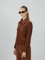 Campera de pana color marrón, con cuello clásico, cierre frontal con botones y dos bolsillos frontales con solapa y botón. Presenta puños con cierre de botón y un diseño estructurado.