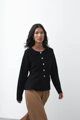 Cardigan negro de tejido de punto con cuello redondo y cierre frontal con botones a contraste. Presenta un corte entallado en la cintura con una silueta levemente evasé y mangas largas.
