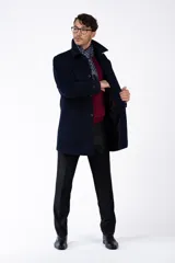 Abrigo clásico de paño azul marino, con cuello solapa, cierre frontal con botones y bolsillos laterales.