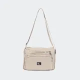 Bandolera color beige con correa larga regulable, cierre superior y bolsillos frontales con cierre.