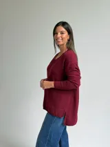 Sweater de punto color bordó, con escote en V, manga larga y costura central vertical decorativa.