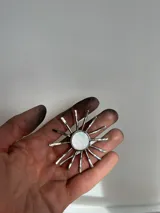Collar con dije en forma de sol hecho a mano con centro de nácar redondo y rayos de plata. Incluye tiento de gamuza largo para usar doble o largo.