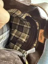Cartera de hombro confeccionada artesanalmente en cuero gamuzado color marrón, con diseño de múltiples volados horizontales y correa ajustable con hebilla metálica.