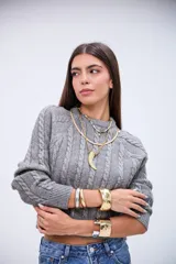 Sweater de punto gris con diseño de trenzas verticales, cuello redondo y corte cropped.