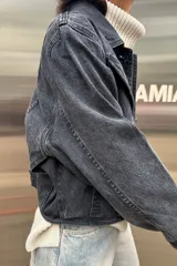 Campera de jean con efecto lavado ácido en color negro, de corte vintage, con costuras reforzadas en hilo color maíz y botones metálicos frontales.