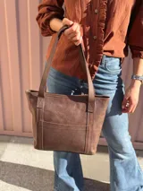 Cartera shopper de cuero color marrón chocolate, con doble asa de hombro, bolsillo frontal externo y diseño estructurado.
