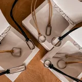 Collar doble con cadena de cuero sintético negro y dije rectangular plateado.