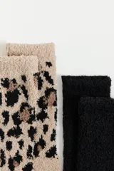 Pack de dos pares de medias de textura afelpada y suave. Incluye un par liso en color negro y un par con estampado animal print en tonos beige y negro.