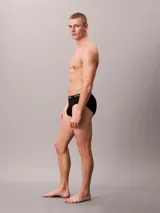 Pack de tres slips negros Calvin Klein de microfibra elástica con cinturilla blanca con el logo de la marca.