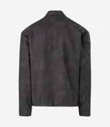 Campera estilo racing confeccionada en poliuretano, con diseño bicolor en negro y beige. Presenta cuello alto con botón a presión, cierre frontal metálico, panel frontal contrastante y franjas laterales deportivas.