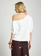 Blusa blanca con diseño de hombro caído, manga corta abullonada y corte holgado.