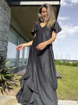 Vestido largo de lurex negro con acabado brillante, escote en V, mangas cortas con volados y falda con tajo lateral que revela un forro interior.