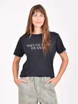 Remera negra de manga corta con cuello redondo y texto estampado en blanco en el pecho que dice "WHEN YOU KNOW YOU KNOW".
