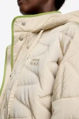 Chaquetón corto de corte línea A, confeccionado en tejido técnico acolchado color beige claro, con costuras en patrón geométrico. Posee cuello subido con capucha integrada, cierre frontal oculto con botones de presión, manga larga con puño elástico y vivos de ribete verde lima al contraste.