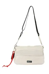 Bandolera color beige con correa ajustable negra y blanca, y un detalle de llavero de cuerda roja y negra. Presenta un bolsillo frontal y un parche con texto en la parte inferior.