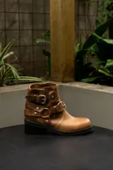 Bota corta de cuero color tostado con hebillas y tachas plateadas.