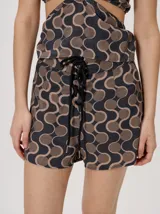 Short holgado de cintura alta con pretina integrada, cordón ajustable delantero y estampado geométrico en tonos rojos y beige.