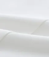 Bermuda de crepé color blanco, de corte holgado y tiro alto, con pliegues frontales y bolsillos laterales con detalle de botones. Confeccionada en poliéster y elastano.