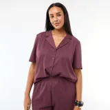 Blusa de manga corta en tejido de punto crepé color bordó, con cuello solapa y cierre frontal de botones.