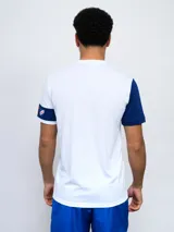Remera de fútbol blanca con manga derecha azul marino y manga izquierda blanca con una banda azul marino y detalles rojos. Tiene el escudo del Club Nacional de Football en el pecho.