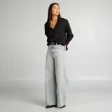 Camisa negra de corte holgado con cuello clásico y mangas largas con puños abotonados.